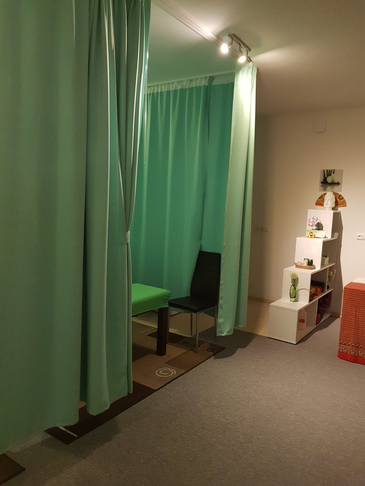 Ruhiger Behandlungsraum mit grünen Vorhängen und vorbereiteter Liege